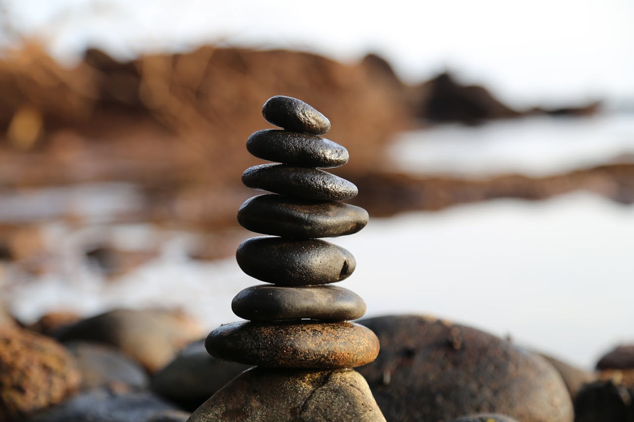 A stack of smooth stones artfully balanced by a waterside, evoking tranquility and zen.